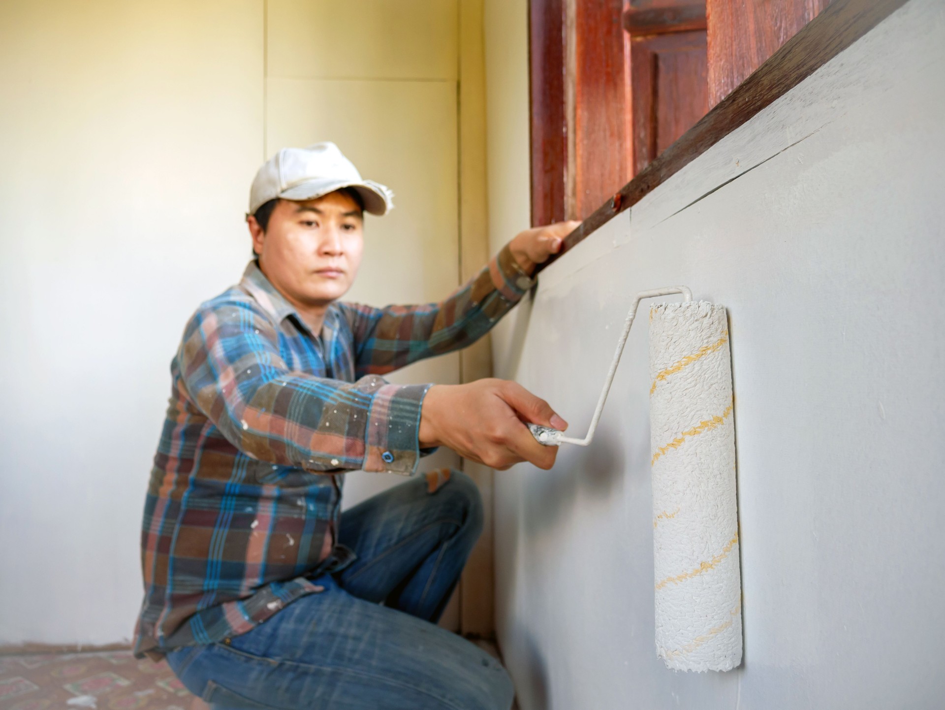 Workers painter are painting the wooden walls of the room white with paint roller,improvement home interior concept.